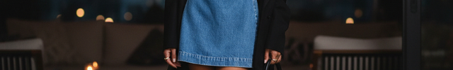 Robe courte en jean bleu, coupe ajustée évasée, col halter et boucles métalliques à la taille.