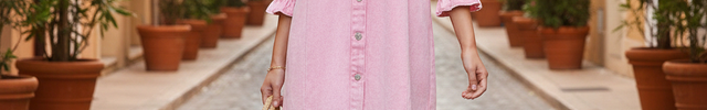 Robe chemise courte en denim rose pastel à manches trois-quarts bouffantes et boutonnage central complet.
