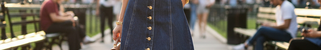 Robe en jean bleu foncé sans manches, courte et cintrée, coupe trapèze avec boutons dorés et col tailleur plongeant.
