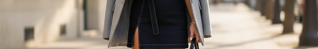 Robe en jean noir courte, coupe droite ceinturée, sans manches avec fente, portée avec veste grise.